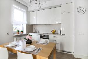eine Küche mit weißen Schränken und einem Holztisch in der Unterkunft Nadwiślańska Apartment in Warschau