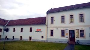 un edificio blanco con un letrero que lee bombeo de misericordia en River Apartmanház, en Jászberény