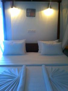 a bed with white sheets and pillows in a room at Secret Palace Guest house in Galle