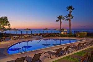 a swimming pool with chairs and the ocean in the background at Carlsbad Seapointe Resort in Carlsbad