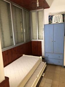 Schlafzimmer mit einem Bett, einem Schrank und Fenstern in der Unterkunft Home Tel Aviv by sourasky medical center ichilov in Tel Aviv
