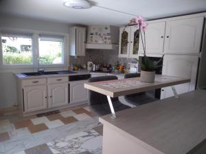 uma cozinha com armários brancos e uma mesa em Chez Colombine em Chaponost