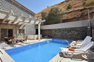 a swimming pool with two chairs next to a building at אחוזת חוף כנרת kinneret village in Tiberias