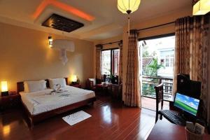 um quarto com uma cama, uma televisão e uma varanda em Long Life Riverside Hotel em Hoi An