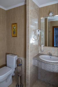 y baño con aseo, lavabo y espejo. en Grand Hotel Eurasia, en Almaty
