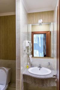 a bathroom with a toilet, sink, mirror and tub at Grand Hotel Eurasia in Almaty