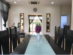 a dining room with a table with chairs and a vase of flowers at Villa Mui Ne Phan Thiet in Mui Ne