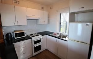 a small kitchen with white cabinets and a white refrigerator at Waterfront Cottages in Greenwell Point