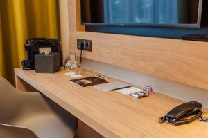 a desk in a hotel room with a phone on it at Centennial Nexus Hotel Tallinn in Tallinn