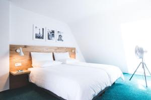 a bedroom with a large white bed and a tripod at Ulmer Münster Hotel in Ulm