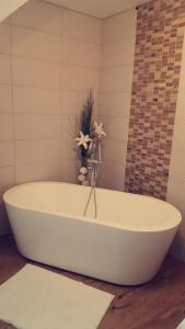 Una bañera blanca con un jarrón de flores. en uebernachtung unna en Unna