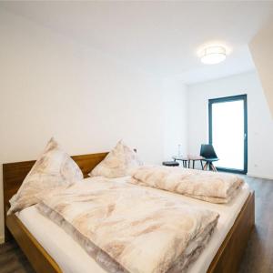 ein großes Bett in einem weißen Zimmer mit einem Tisch in der Unterkunft Hotel Seeadler in Friedrichshafen
