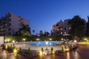 una piscina por la noche con edificios en el fondo en The Jolo en Limassol