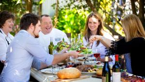 Un gruppo di persone seduti intorno a un tavolo che mangiano cibo di Stylish North Adelaide Apartments a Adelaide