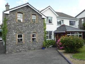een huis met een stenen gebouw op een oprit bij Pearse Lodge in Sligo
