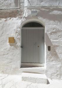 una puerta blanca en un edificio de piedra blanca con escalones en Torretta Alchimia, en Ostuni