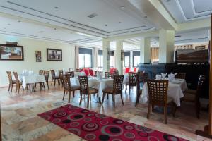 Hôtel Jawharat El Jadida في الجديدة: غرفة طعام بطاولات وكراسي وبيانو