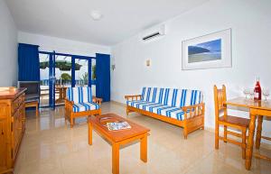sala de estar con mesa y muebles de color azul y blanco en Apartamentos Club Pocillos, en Puerto del Carmen