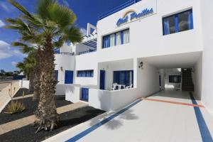 a white building with a palm tree in front of it at Apartamentos Club Pocillos in Puerto del Carmen