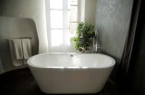 eine weiße Badewanne im Bad mit Fenster in der Unterkunft la maison aux bonsais in Saint-Paul-de-Vence