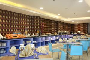 ein Restaurant mit blauen Tischen und Stühlen sowie einer Küche in der Unterkunft Horison Express Sentani in Jayapura
