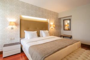 een hotelkamer met een groot bed en een spiegel bij Forte de São Francisco Hotel Chaves in Chaves