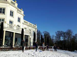 een groep mensen die in de sneeuw voor een gebouw staan bij verzorgde kamer in monumentenpand in Arnhem