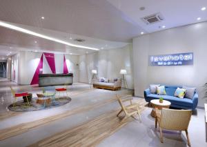 a lobby with a blue couch and a piano at favehotel Madiun in Madiun