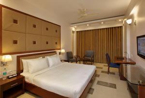 a hotel room with a bed and a table and chairs at Lemon Tree Hotel Baddi in Baddi