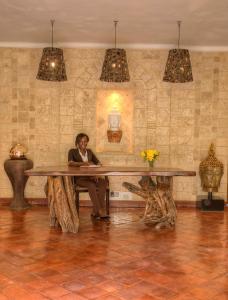The Aberdare Country Club في Mweiga: امرأة تجلس على طاولة كبيرة في غرفة