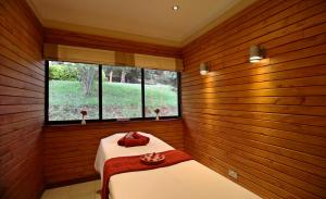 a room with two beds in a room with wooden walls at The Aberdare Country Club in Mweiga