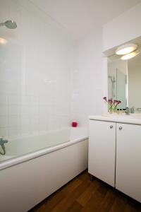 Baño blanco con bañera y lavamanos en Séjours & Affaires Reims Clairmarais, en Reims