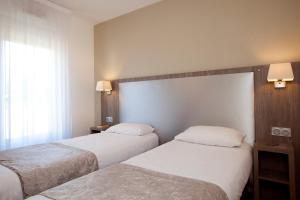 a hotel room with two beds and two lamps at Séjours & Affaires Reims Clairmarais in Reims