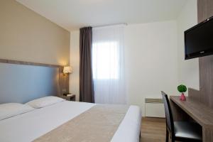 a hotel room with a bed and a television at Séjours & Affaires Reims Clairmarais in Reims