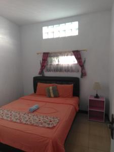 1 dormitorio con cama con sábanas de color naranja y ventana en Runia Lembang, en Bandung