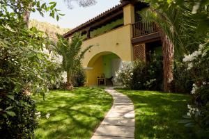 un jardin avec une passerelle menant à une maison dans l'établissement Forte Village Resort - Pineta, à Santa Margherita di Pula