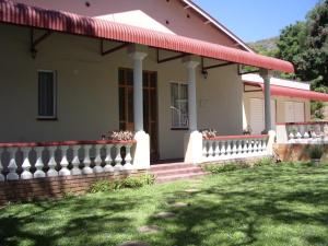 une maison avec une clôture blanche et une terrasse couverte dans l'établissement Dee's BnB, à Pretoria