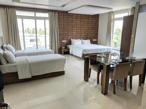 a hotel room with two beds and a dining table at Clyford Suites in Bangalore