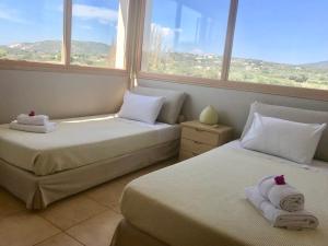 two beds in a room with two windows at Dolce Vita Villas in Svoronata