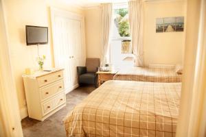 una camera con 2 letti, una scrivania e una TV di Burford Lodge Guest House a Ardglass