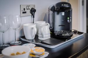 a counter with a coffee maker and wine glasses at Lymm Boutique Rooms in Lymm