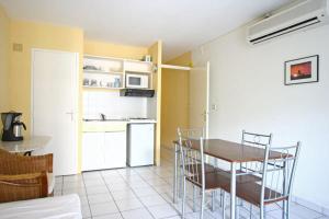 eine Küche und ein Esszimmer mit einem Tisch und Stühlen in der Unterkunft Hotel-appart Les Manguiers in Saint-Denis
