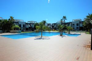 a large swimming pool with palm trees and buildings at Oasis Beach Gabriel in Orihuela Costa