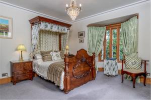a bedroom with a wooden bed and a chandelier at Taldraeth - Old Vicarage Guest House in Penrhyndeudreath