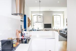 a kitchen with white cabinets and a living room at Luxury and Beautiful Apartment in Chiado in Lisbon