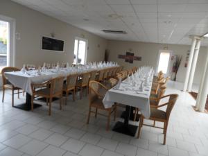 une grande salle à manger avec des tables et des chaises blanches dans l'établissement Au Sauvage, à Lorris