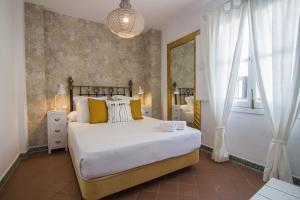 a bedroom with a large white bed with yellow pillows at Apartamentos Boutique Vida in Seville