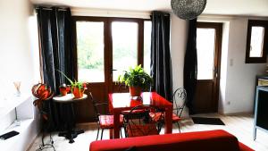 ein Wohnzimmer mit einem roten Tisch, Stühlen und Fenstern in der Unterkunft Le vieux Pressoir in Saint-Germain-lès-Arlay