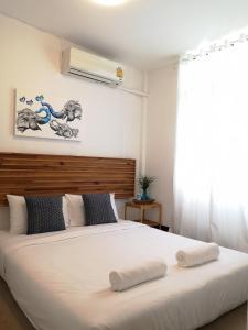 Un dormitorio con una gran cama blanca con dos toallas encima. en Cozy by Funwahn, en Chiang Mai