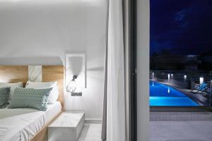 a bedroom with a bed and a view of a pool at Albatros Suites in Nea Vrasna